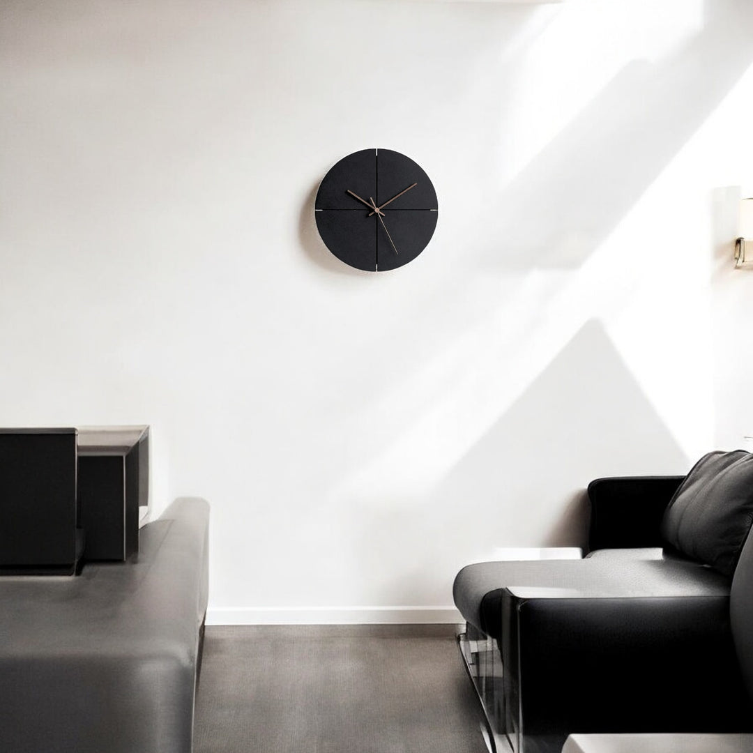 Minimalist black clock with brown hands closeup on wall